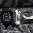 Rugged square smartwatches with a built-in flashlight resting on dark rock
